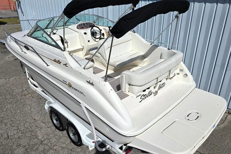 Slide: The Image of 1997 Sea Ray 240 Sundancer boat on trailer, featuring white seating and black canopy. - 2