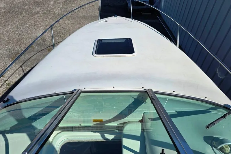 Slide: The Image of 1997 Sea Ray 240 Sundancer boat deck with windshield and hatch, docked outdoors. - 21