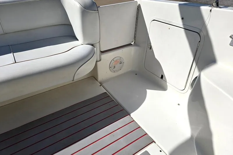 Slide: The Image of Interior of 1997 Sea Ray 240 Sundancer boat with white seating and storage compartment. - 28