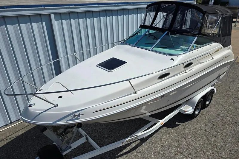 Slide: The Image of 1997 Sea Ray 240 Sundancer boat on trailer, white exterior, docked near metal building. - 30