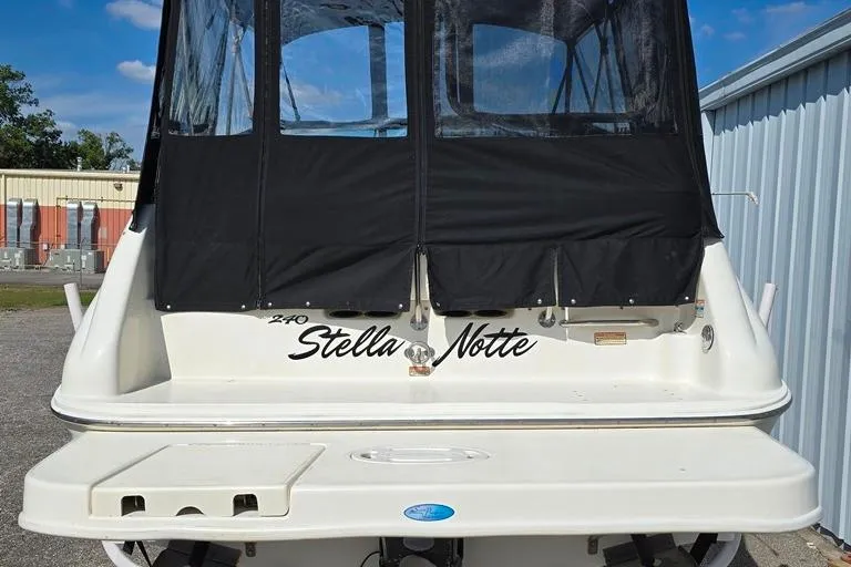 Slide: The Image of 1997 Sea Ray 240 Sundancer boat with black canopy, named "Stella Notte," docked outdoors. - 31