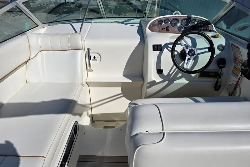 Slide: The Image of 1997 Sea Ray 240 Sundancer boat interior with white seating and steering wheel. - 5