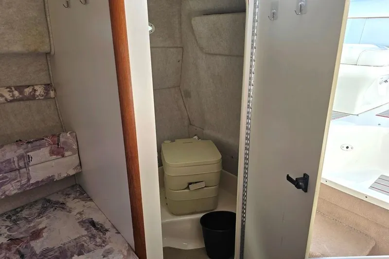 Slide: The Image of Interior of 1997 Sea Ray 240 Sundancer showing compact bathroom and seating area. - 9