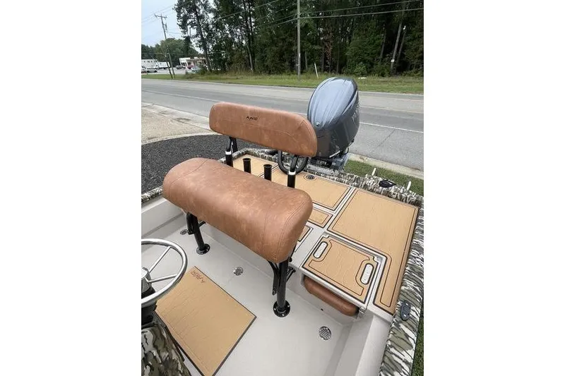 Slide: The Image of 2026 Avid 21 FSX boat interior with tan seating and deck, parked roadside. - 4