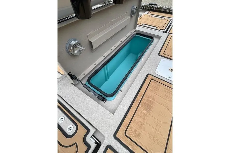 Slide: The Image of 2026 Avid 21 FSX boat storage compartment with teal interior and wood-patterned deck. - 5