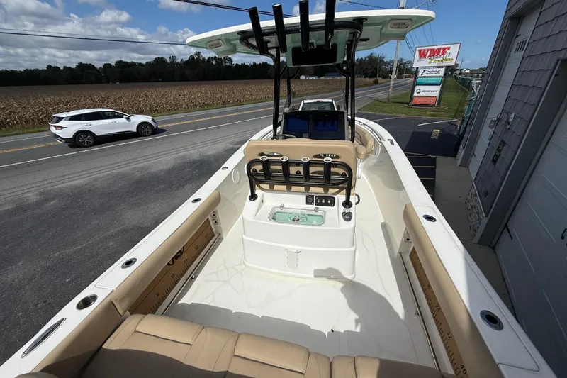 Slide: The Image of 2020 NauticStar 2602 Legacy boat interior with beige seating, parked near a road. - 14