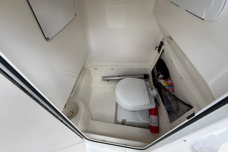 Slide: The Image of 2020 NauticStar 2602 Legacy boat interior with compact marine toilet and storage. - 21
