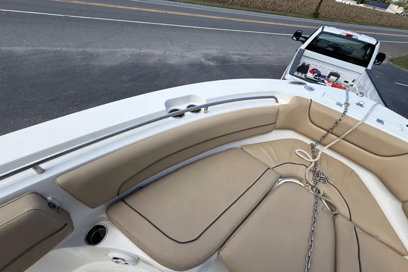 Slide: The Image of 2020 NauticStar 2602 Legacy boat interior with tan seating, parked near a road. - 23