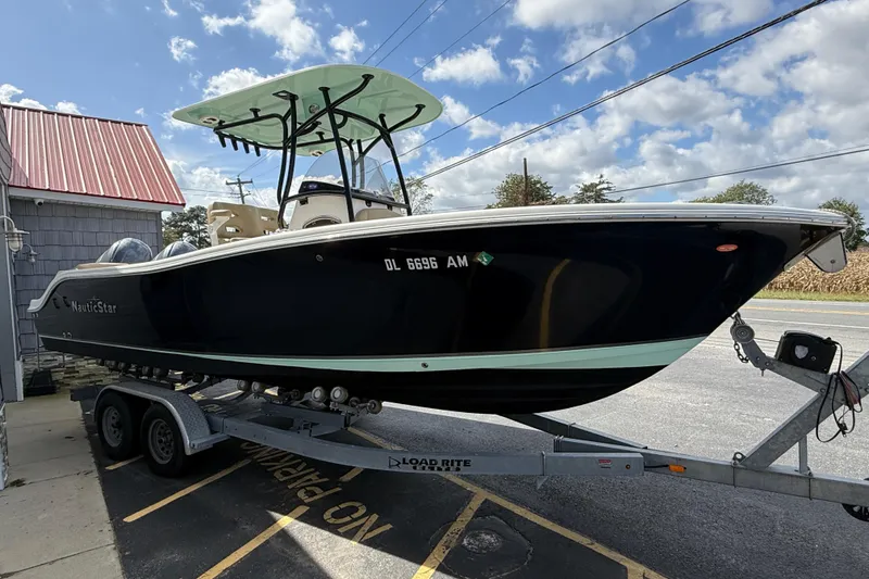 Slide: The Image of 2020 NauticStar 2602 Legacy boat on trailer, parked outdoors under a blue sky. - 9
