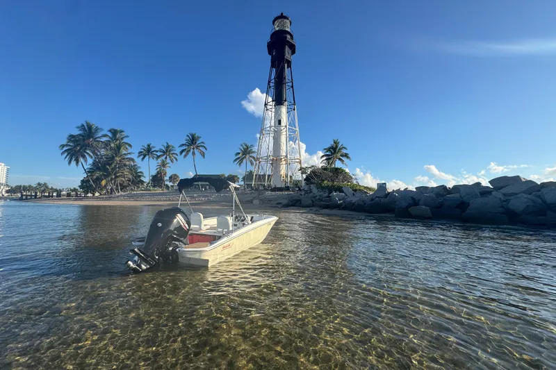 Slide: The Image of 2021 Boston Whaler 160 Super Sport near lighthouse, clear water, and palm trees. - 12