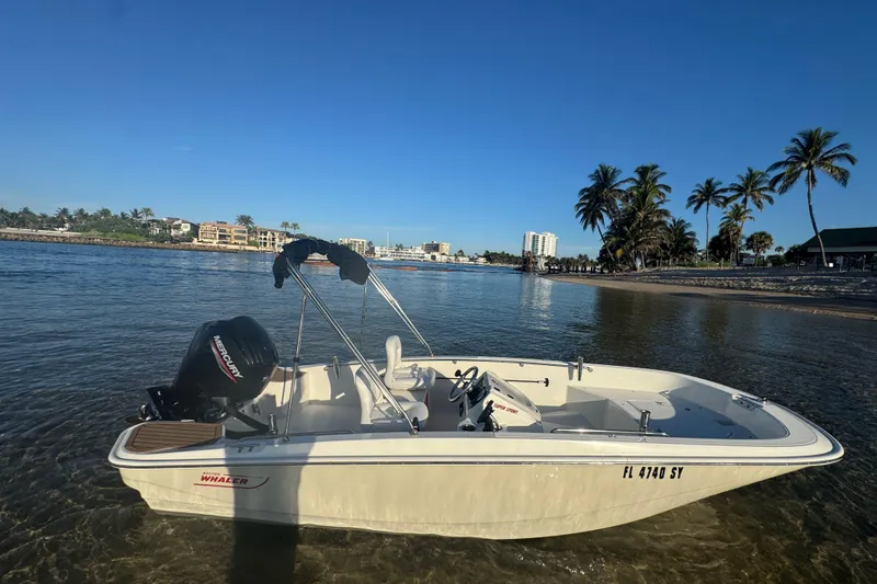 Slide: The Image of 2021 Boston Whaler 160 Super Sport boat near a tropical shoreline with palm trees. - 2