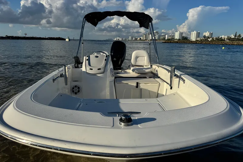 Slide: The Image of 2021 Boston Whaler 160 Super Sport boat with navigation system, docked near rocky shore. - 21