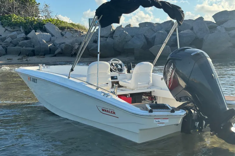 Slide: The Image of 2021 Boston Whaler 160 Super Sport boat docked near rocky shoreline. - 9