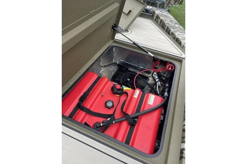 Slide: The Image of Open storage compartment of 2026 Avid 18 Commander boat with red fuel tanks. - 4