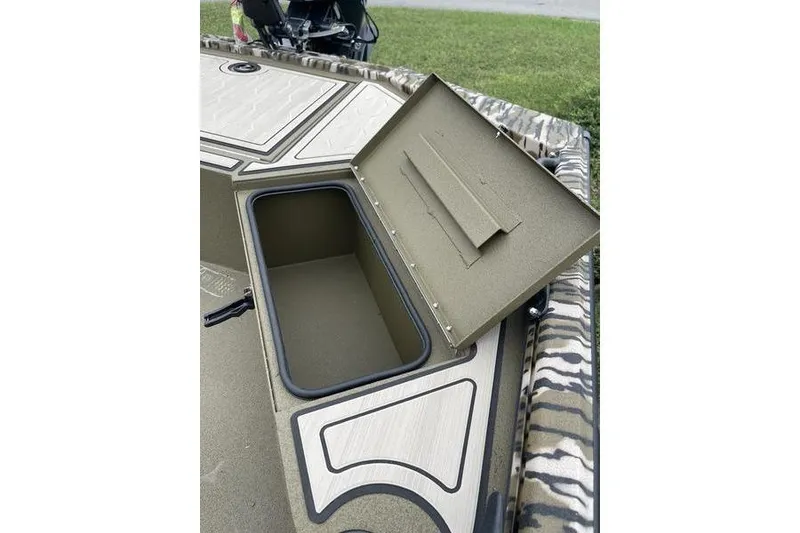 Slide: The Image of Open storage compartment on 2026 Avid 18 Commander boat, featuring camo design. - 5