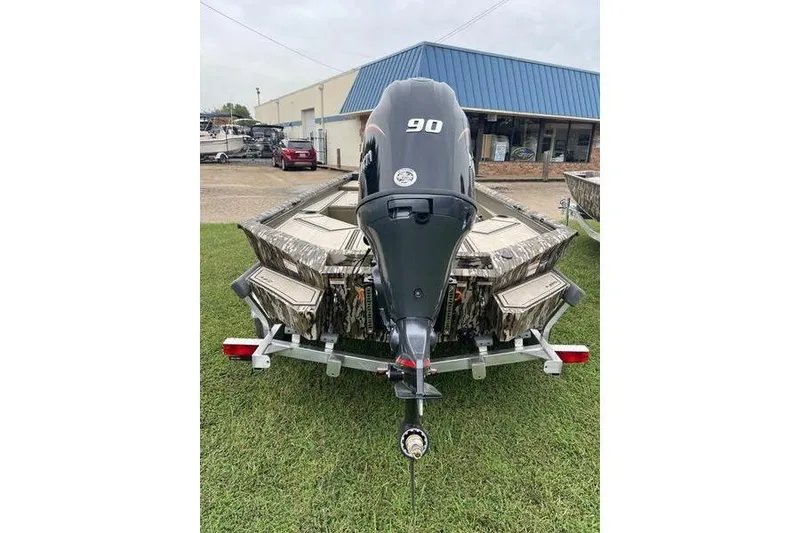 Slide: The Image of 2026 Avid 18 Commander boat with 90 HP engine on trailer, parked on grass. - 7