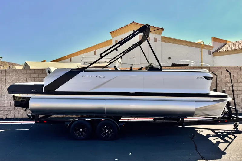 Slide: The Image of 2026 Manitou Cruise 22 Max pontoon boat on trailer, parked outdoors. - 0
