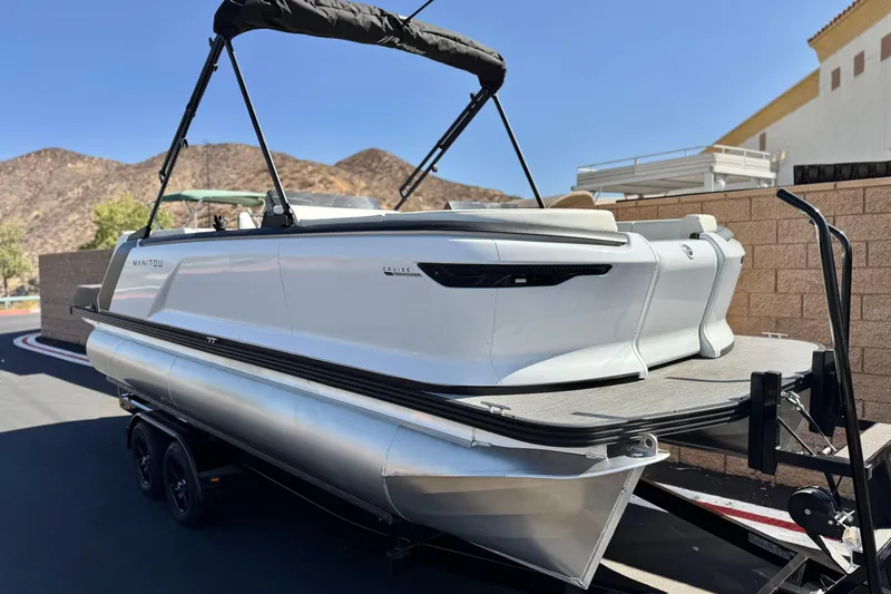 Slide: The Image of 2026 Manitou Cruise 22 Max pontoon boat on trailer, parked outdoors. - 1