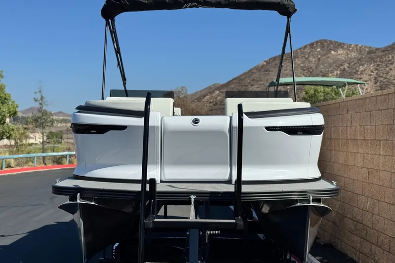 Slide: The Image of 2026 Manitou Cruise 22 Max pontoon boat, rear view, parked outdoors. - 2