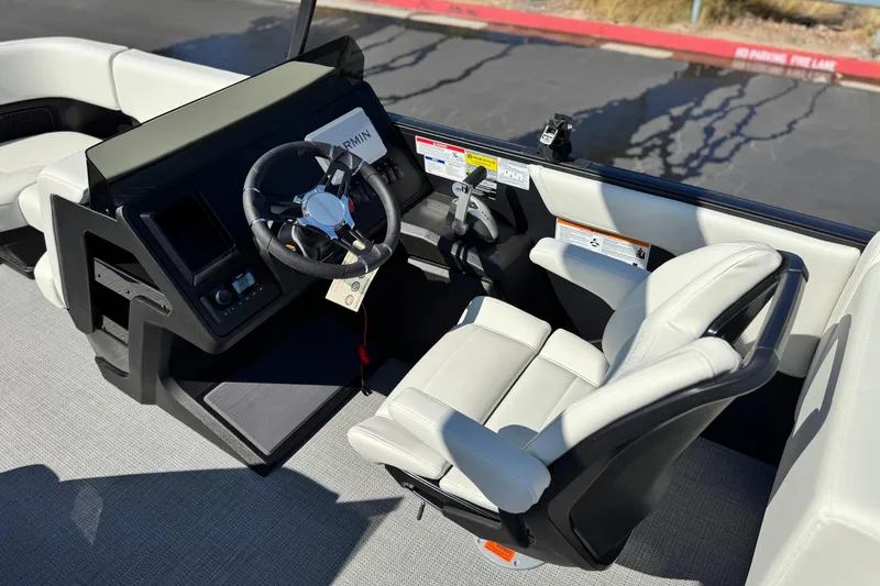 Slide: The Image of 2026 Manitou Cruise 22 Max boat cockpit with steering wheel and white captain's chair. - 23
