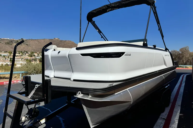 Slide: The Image of 2026 Manitou Cruise 22 Max pontoon boat on trailer, scenic background. - 3