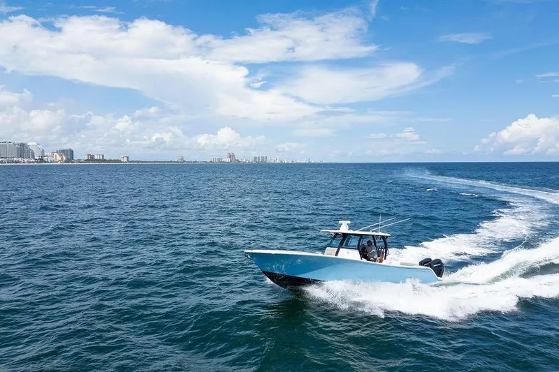 Slide: The Image of 2023 Sportsman Open 322 Center Console boat cruising on open ocean under clear blue sky. - 11