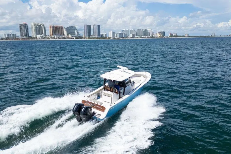 Slide: The Image of 2023 Sportsman Open 322 Center Console cruising near city skyline on ocean. - 13