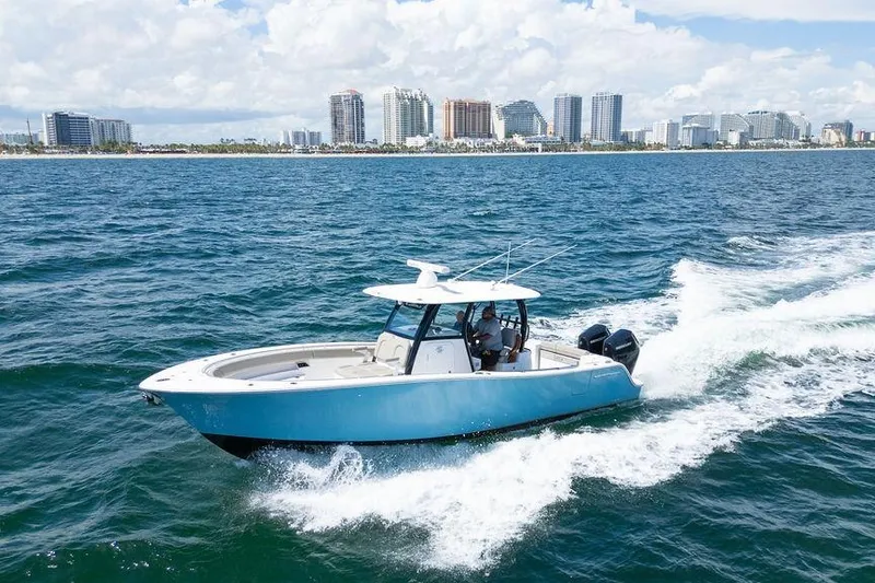 Slide: The Image of 2023 Sportsman Open 322 Center Console cruising near city skyline on blue ocean. - 18