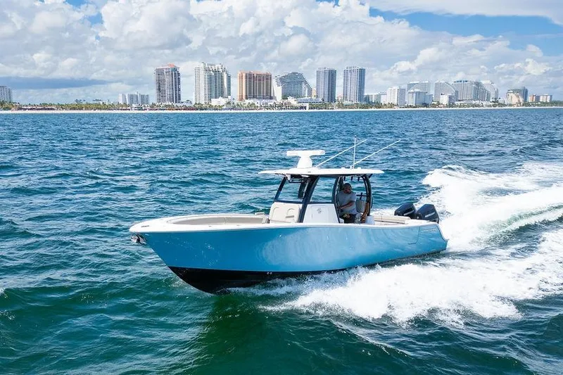 Slide: The Image of 2023 Sportsman Open 322 Center Console cruising on ocean with city skyline backdrop. - 19