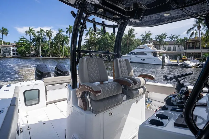 Slide: The Image of 2023 Sportsman Open 322 Center Console boat interior with luxurious seating and scenic waterfront view. - 50