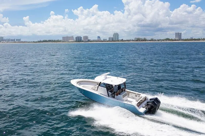 Slide: The Image of 2023 Sportsman Open 322 Center Console boat cruising on ocean near city skyline. - 8