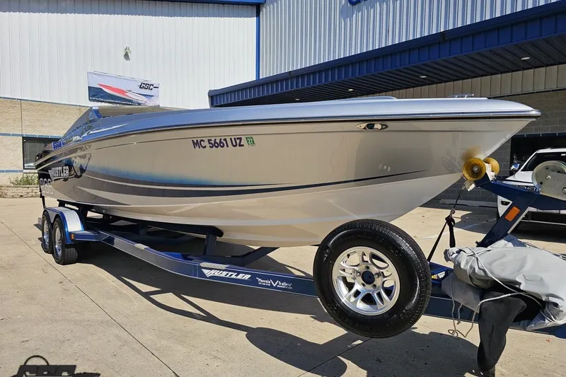 Slide: The Image of 2010 Hustler 266 Classic speedboat on trailer outside a building. - 14