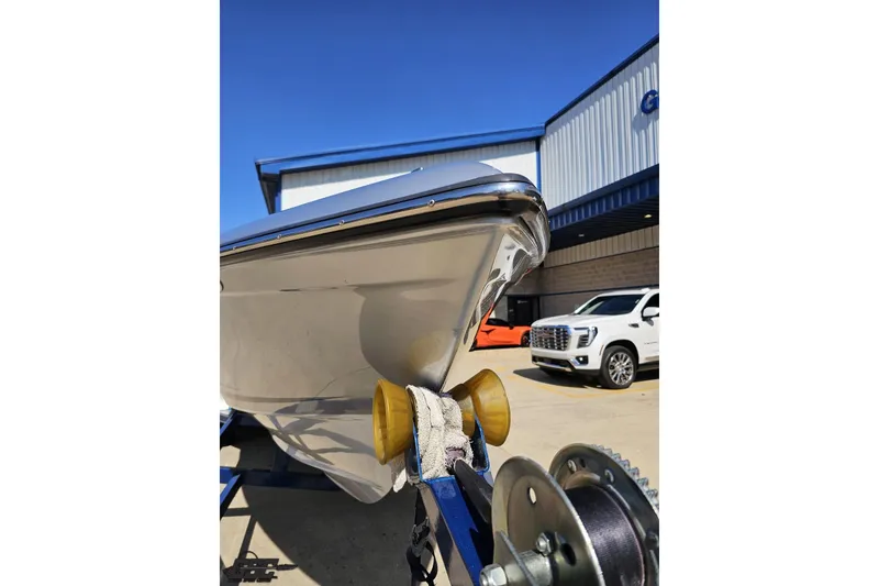 Slide: The Image of 2010 Hustler 266 Classic boat on trailer, parked near vehicles and building. - 15