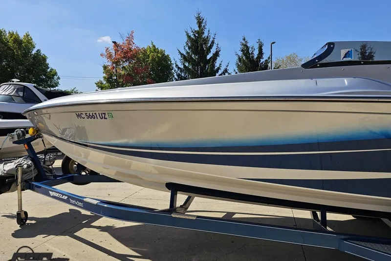 Slide: The Image of 2010 Hustler 266 Classic boat on trailer, parked outdoors under clear blue sky. - 20