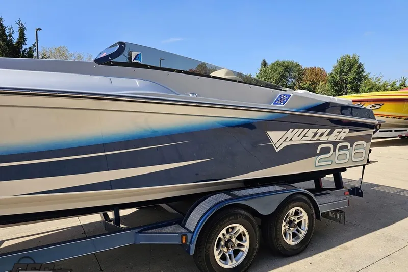 Slide: The Image of 2010 Hustler 266 Classic speedboat on trailer, parked outdoors. - 21