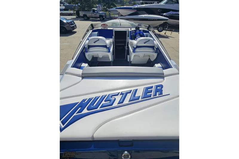 Slide: The Image of 2010 Hustler 266 Classic speedboat with blue and white interior, parked outdoors. - 39