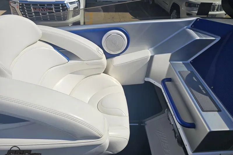 Slide: The Image of Interior of a 2010 Hustler 266 Classic boat with white seating and blue accents. - 52