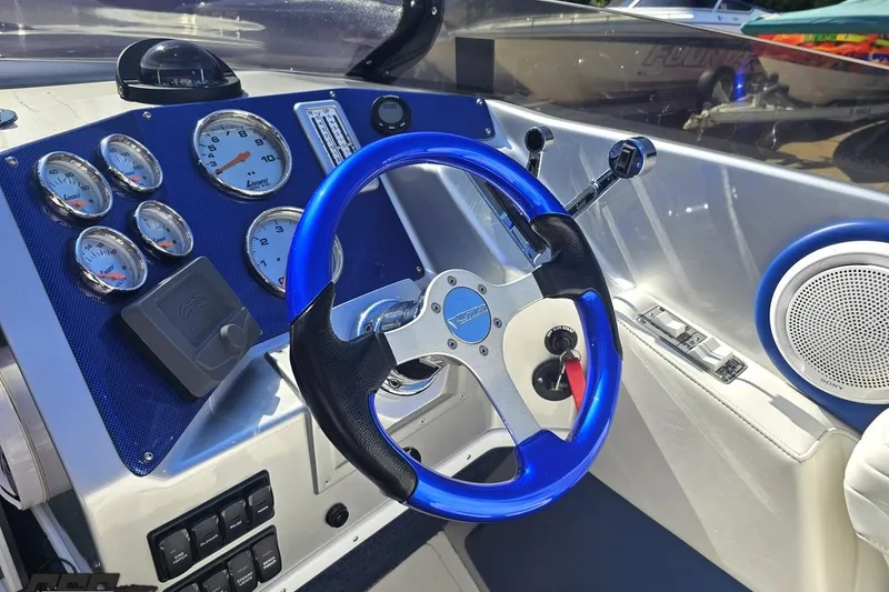 Slide: The Image of 2010 Hustler 266 Classic boat dashboard with blue steering wheel and gauges. - 54