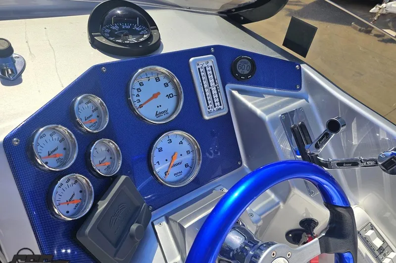 Slide: The Image of Dashboard of a 2010 Hustler 266 Classic boat with gauges and blue steering wheel. - 55