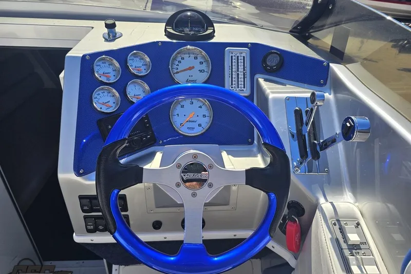 Slide: The Image of Dashboard of a 2010 Hustler 266 Classic boat with blue steering wheel and gauges. - 56