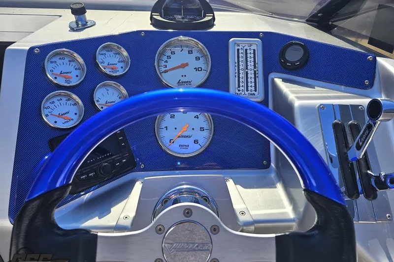 Slide: The Image of Dashboard of a 2010 Hustler 266 Classic boat with blue steering wheel and gauges. - 57
