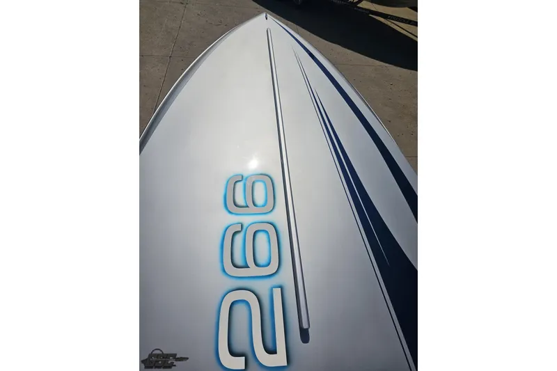 Slide: The Image of 2010 Hustler 266 Classic boat with sleek design and blue accents on deck. - 62