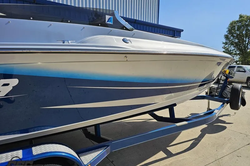 Slide: The Image of 2010 Hustler 266 Classic boat on trailer, blue and white design, parked outdoors. - 8