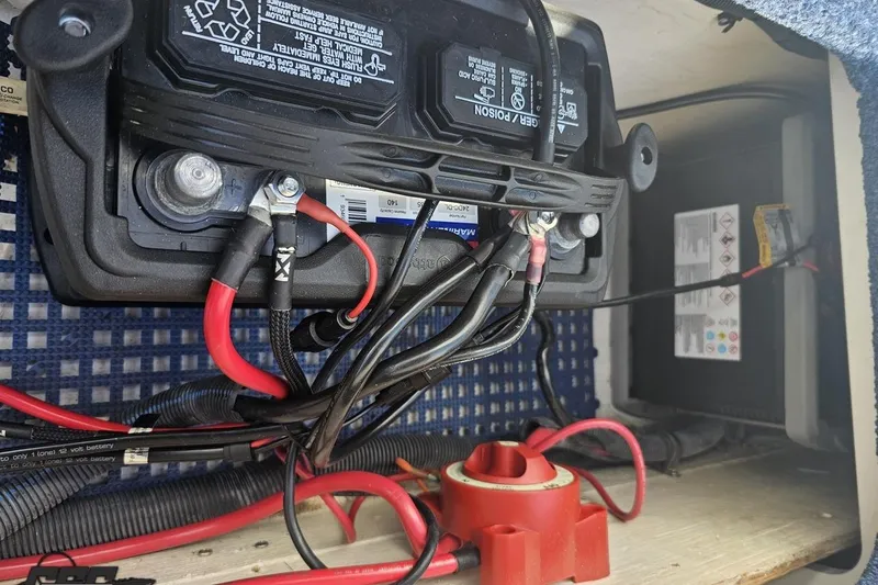 Slide: The Image of Battery compartment of a 2010 Hustler 266 Classic with connected cables and wiring. - 85