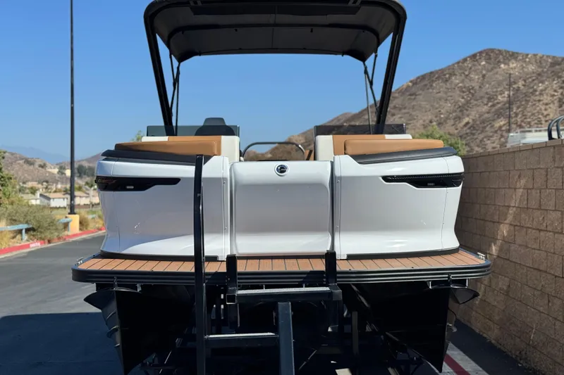 Slide: The Image of 2026 Manitou EXPLORE 22 boat, rear view, parked outdoors with scenic mountain backdrop. - 2