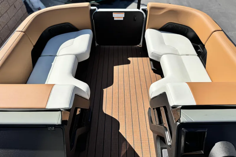 Slide: The Image of 2026 Manitou EXPLORE 22 boat interior with tan and white seating, wood-style flooring. - 9