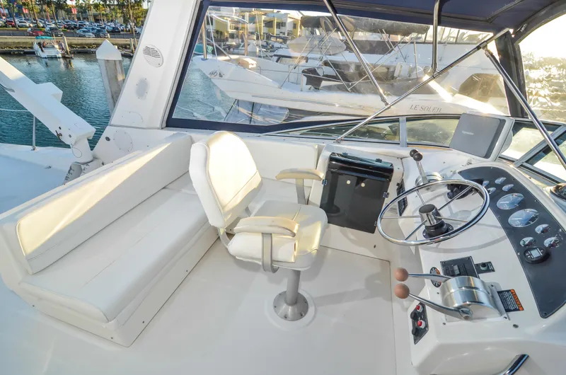 Slide: The Image of 2002 Bayliner 4788 Pilot House Motoryacht helm with seating and controls, docked at marina. - 12