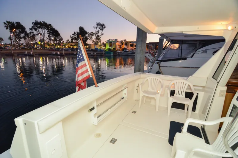 Slide: The Image of 2002 Bayliner 4788 Pilot House Motoryacht deck with chairs and American flag at sunset. - 20