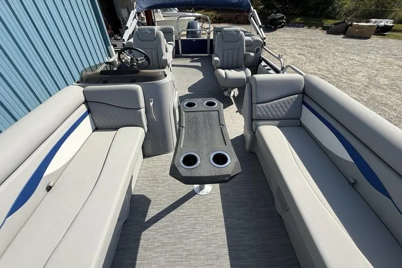 Slide: The Image of 2023 Bennington 22 boat interior with gray seating and central table, docked outdoors. - 21