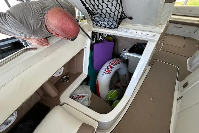 Slide: The Image of 2011 Cobalt 302 boat storage compartment with various items, including a cooler and sports equipment. - 15